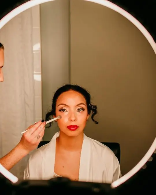 Tori applying a bride’s makeup, seen through a ring light