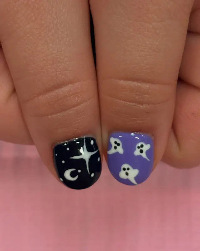 Close view of two nails painted with stars, a moon and ghosts