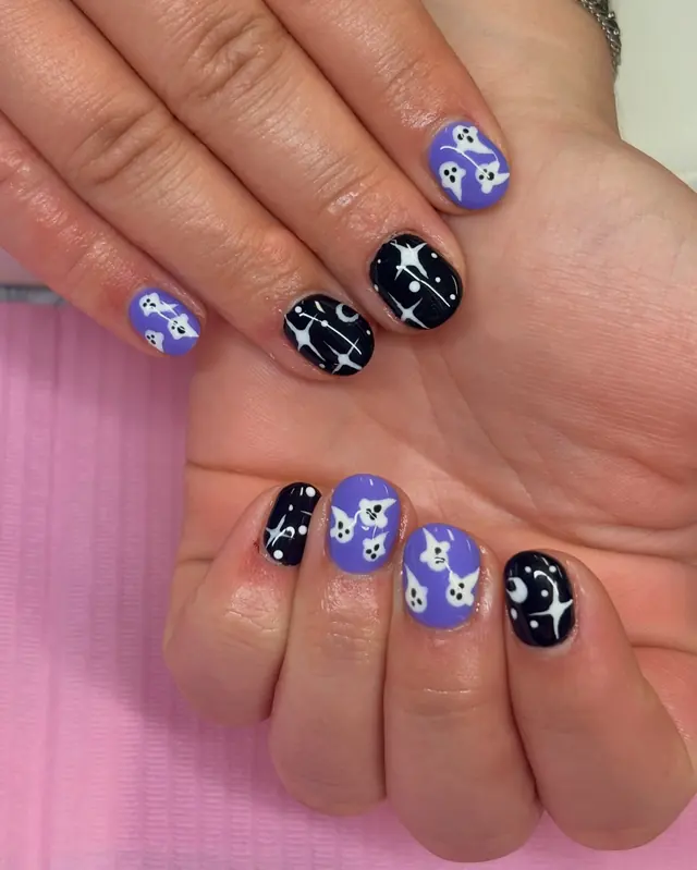 Purple and black gel nails with hand-painted ghosts and stars