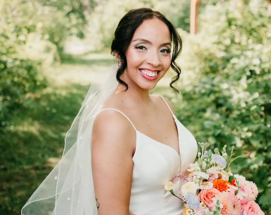 The bride outdoors in her veil, smiling, with her makeup finished