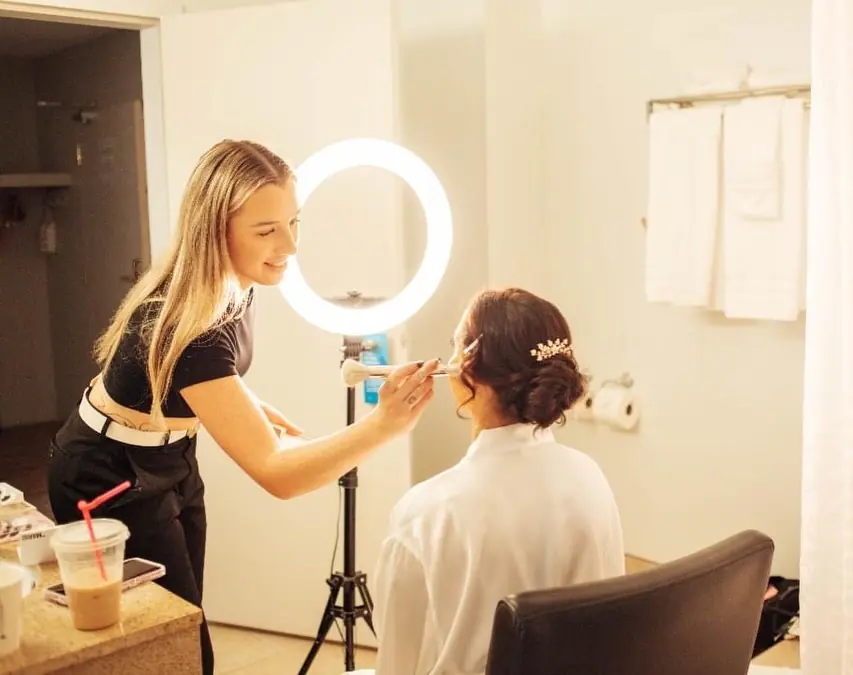 Tori applying the bride’s makeup beside a ring light