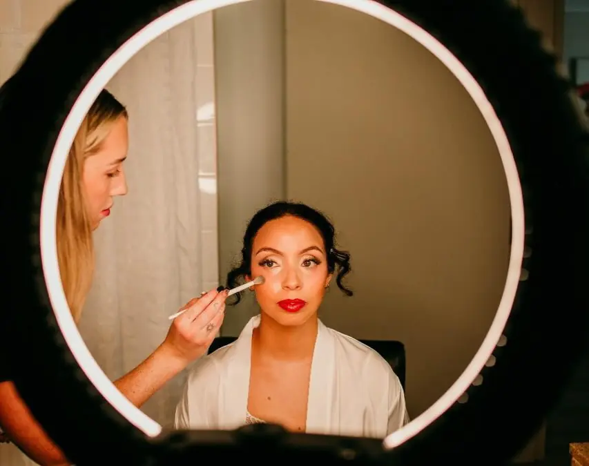 Tori applying a bride’s makeup, seen through a ring light