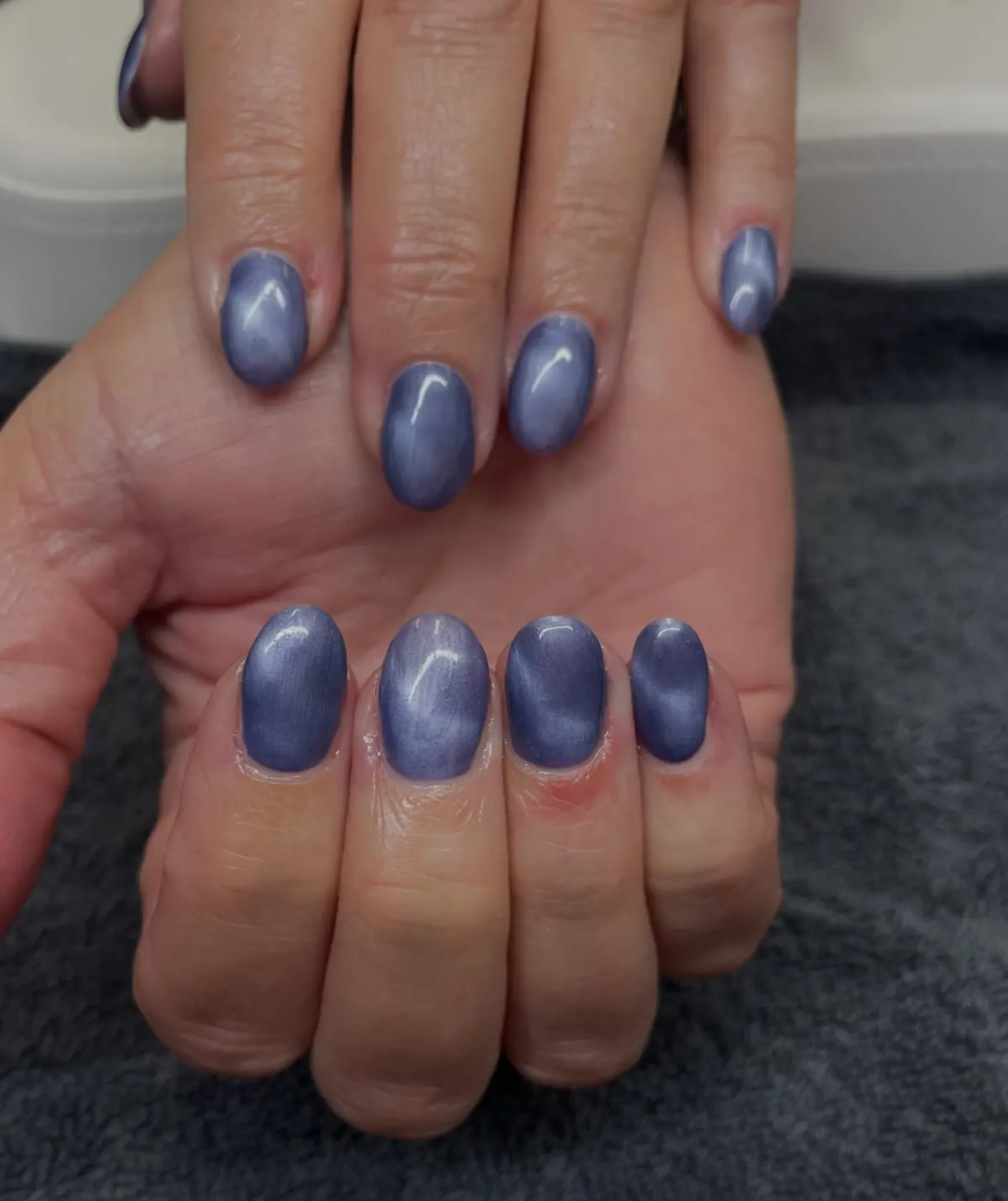 A client’s hands with blue cat eye gel nails
